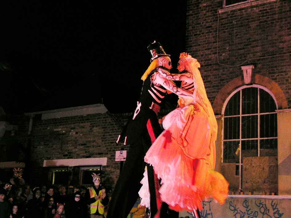 Two performers in Día de los Muertos costume dancing on stilts