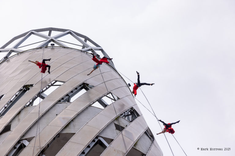 Four aerial performers suspended from top of tall building