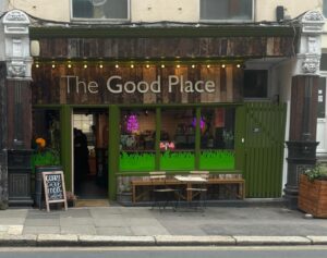 A cafe called The Good Place is seen, it's painted green with wooden boarding behind white lettering.